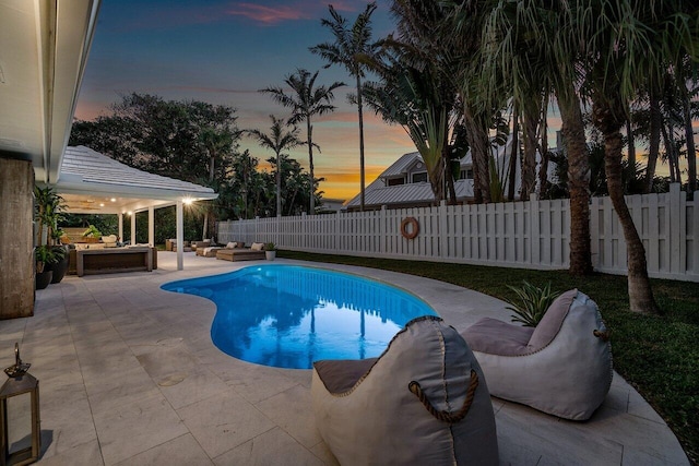 pool at dusk featuring a patio area and an outdoor living space