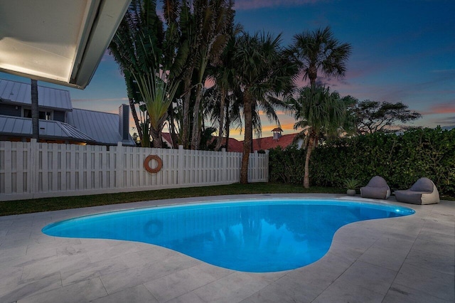 pool at dusk with a patio area