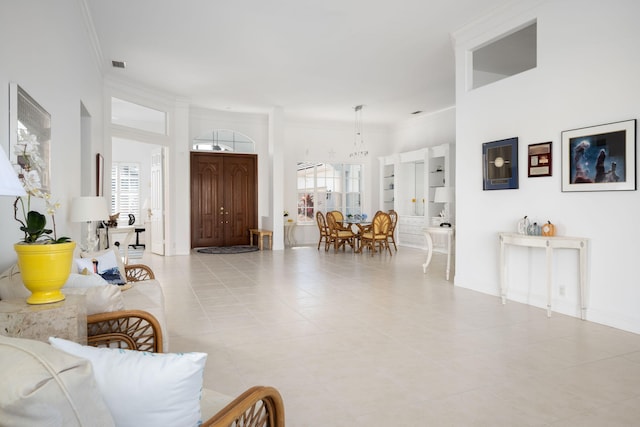 tiled living room featuring ornamental molding, built in features, a wealth of natural light, and a notable chandelier