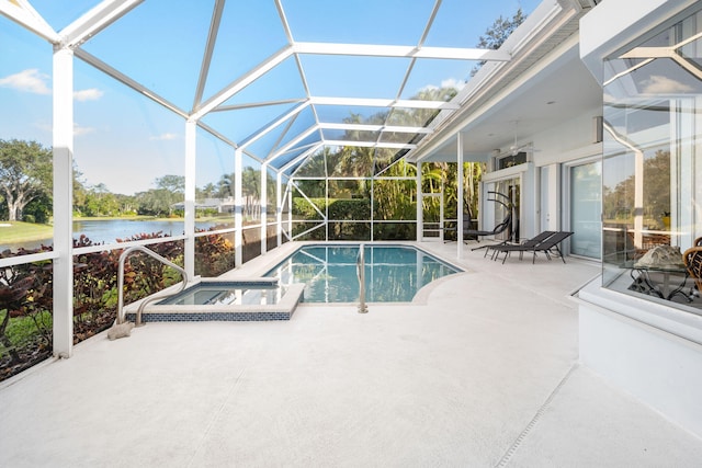 view of pool with glass enclosure, a patio area, a water view, and an in ground hot tub