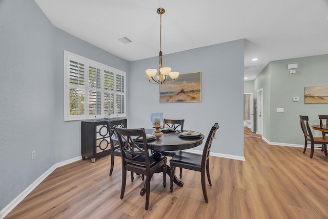 dining space with a notable chandelier and light hardwood / wood-style floors