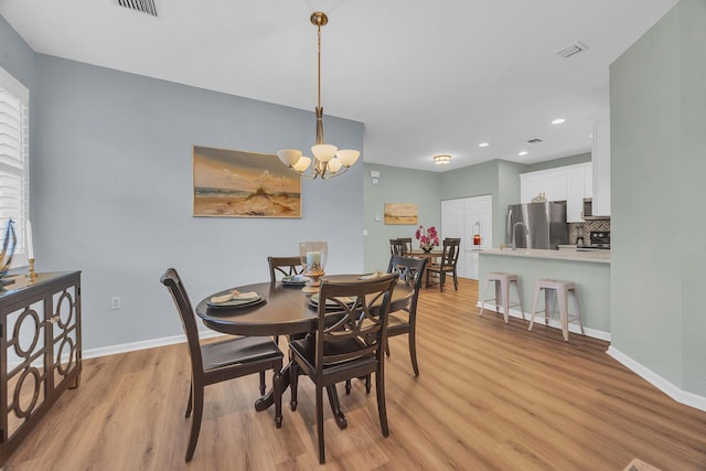 dining area featuring light hardwood / wood-style floors and an inviting chandelier