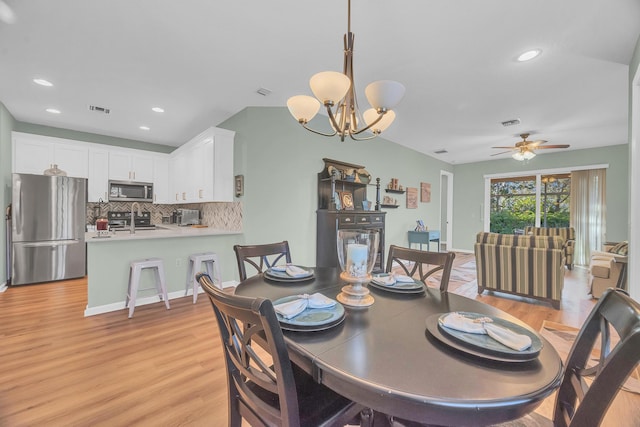 dining room with ceiling fan with notable chandelier and light wood-type flooring