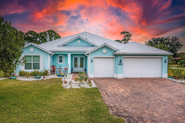 view of front of house featuring a garage, a lawn, and french doors