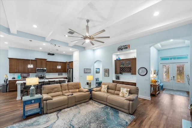 living room with ceiling fan, a high ceiling, dark hardwood / wood-style flooring, and beamed ceiling