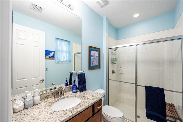 bathroom featuring vanity, a shower with shower door, a textured ceiling, and toilet