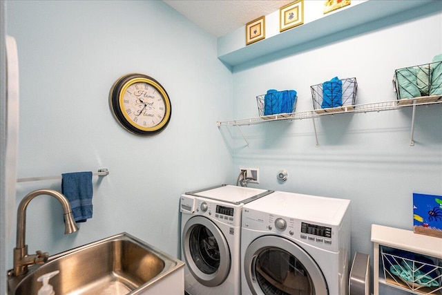 clothes washing area with sink, a textured ceiling, and separate washer and dryer