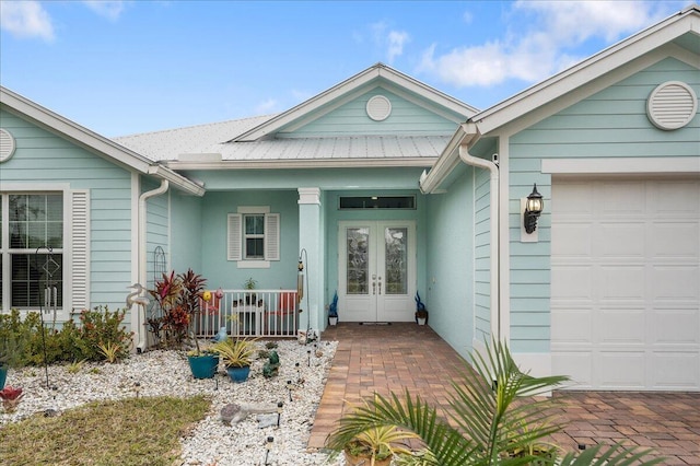 view of exterior entry with french doors, a porch, and a garage