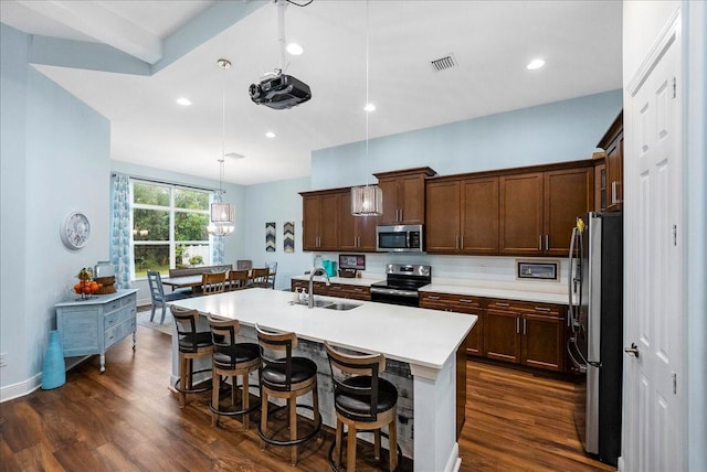 kitchen with decorative light fixtures, a center island with sink, sink, and appliances with stainless steel finishes