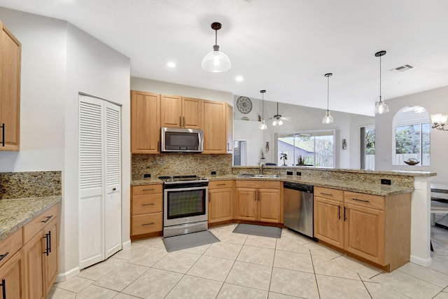 kitchen with kitchen peninsula, ceiling fan, appliances with stainless steel finishes, decorative light fixtures, and light stone countertops