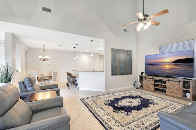 tiled living room featuring a towering ceiling and ceiling fan with notable chandelier