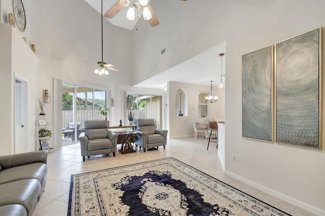 tiled living room featuring ceiling fan with notable chandelier and high vaulted ceiling