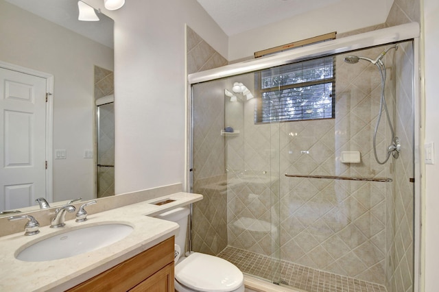 bathroom with toilet, vanity, and a shower with shower door