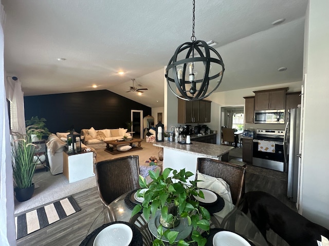 dining area featuring dark hardwood / wood-style flooring, ceiling fan with notable chandelier, and vaulted ceiling