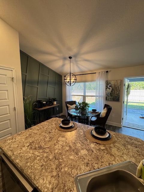 kitchen with light stone countertops, decorative light fixtures, and a healthy amount of sunlight