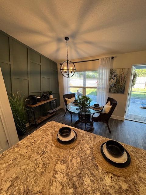 dining area featuring a textured ceiling, an inviting chandelier, and dark wood-type flooring