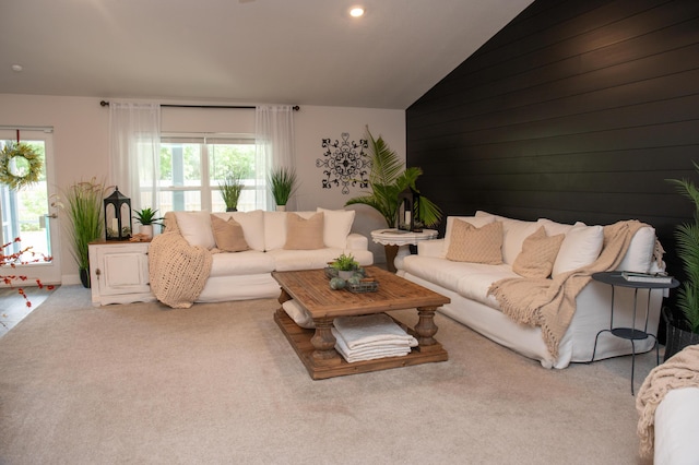 carpeted living room with wood walls and vaulted ceiling