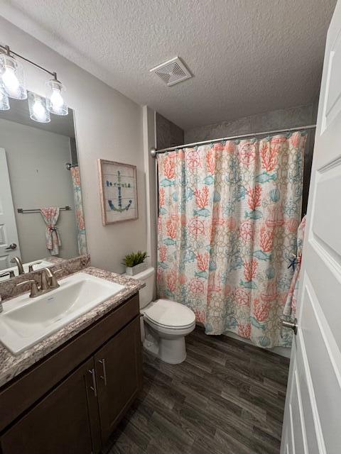 bathroom featuring hardwood / wood-style floors, vanity, toilet, a textured ceiling, and walk in shower