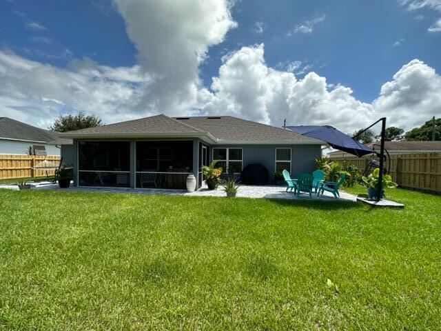 back of property with a sunroom, a yard, and a patio