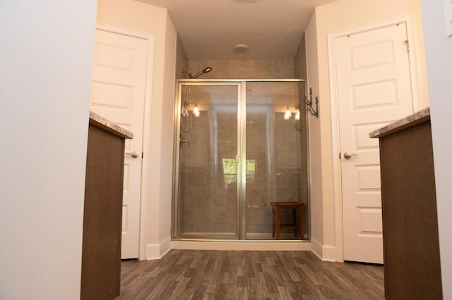 bathroom with hardwood / wood-style flooring, walk in shower, and a textured ceiling