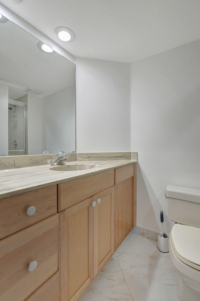 bathroom featuring vanity, a shower with door, and toilet