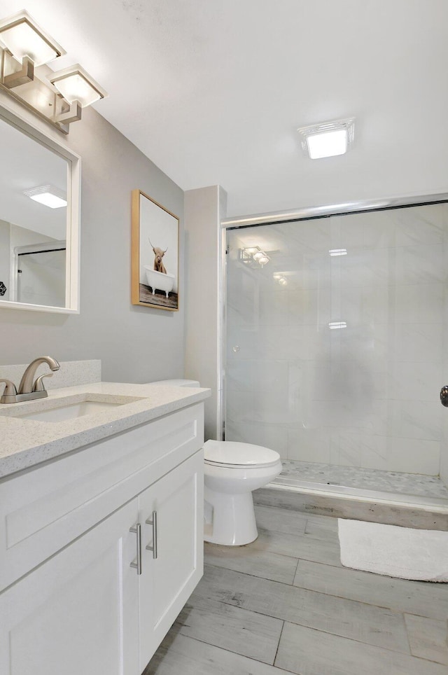 bathroom with an enclosed shower, vanity, and toilet