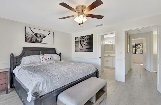 bedroom featuring ceiling fan, sink, ensuite bathroom, and light wood-type flooring