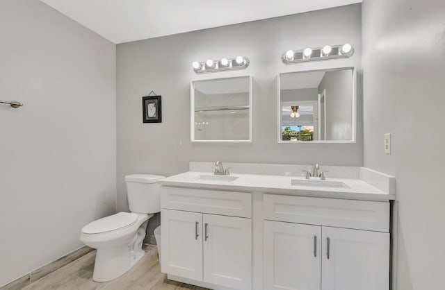 bathroom with hardwood / wood-style flooring, vanity, toilet, and a shower with door