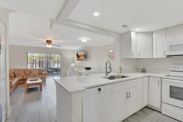 kitchen with kitchen peninsula, white appliances, ceiling fan, sink, and white cabinets