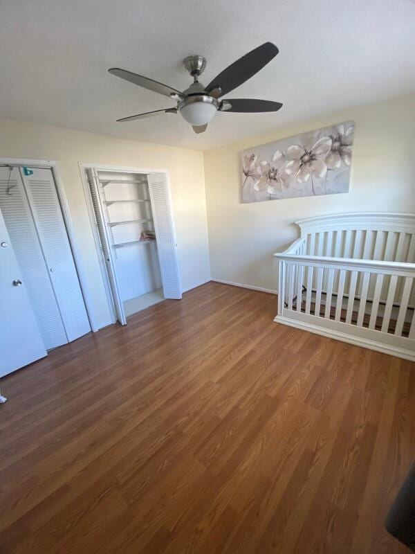 unfurnished bedroom featuring hardwood / wood-style flooring, ceiling fan, and two closets