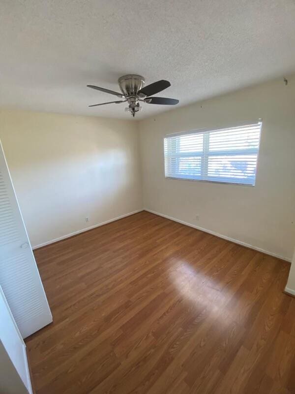 unfurnished room with a textured ceiling, ceiling fan, and dark hardwood / wood-style floors