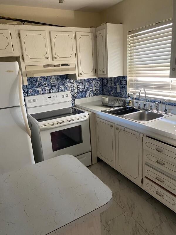 kitchen with white electric range oven, backsplash, and sink