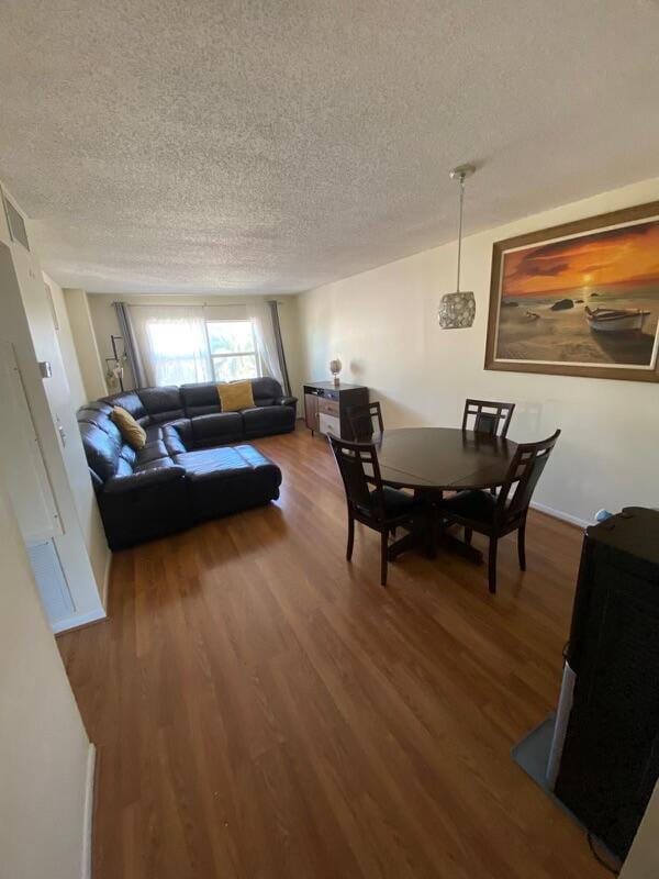 dining space with hardwood / wood-style floors and a textured ceiling