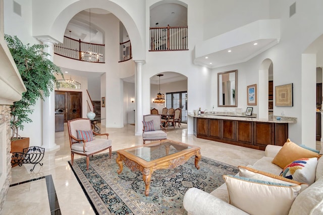 living room with decorative columns, a chandelier, and a high ceiling