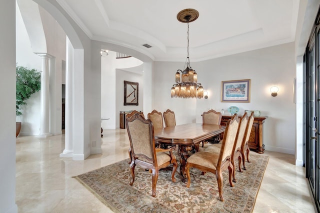 dining room featuring a tray ceiling, ornate columns, and an inviting chandelier