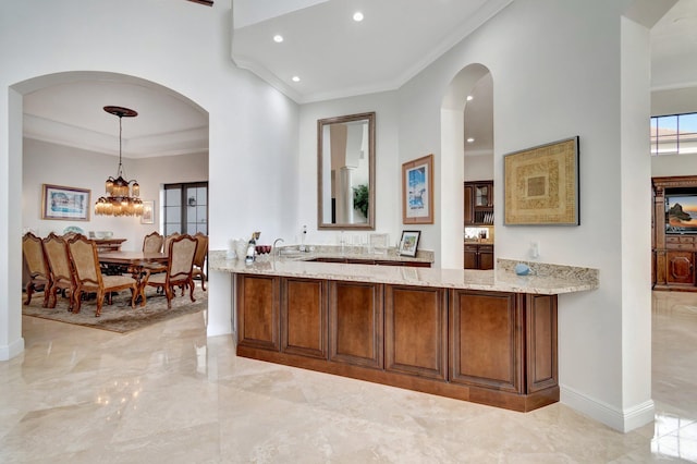 interior space with light stone countertops, sink, an inviting chandelier, pendant lighting, and ornamental molding