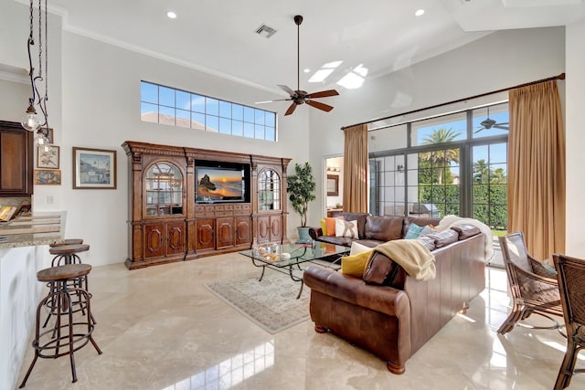 living room featuring a towering ceiling, ceiling fan, and ornamental molding