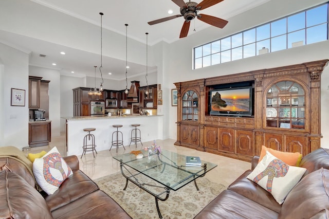 living room featuring a high ceiling, ceiling fan, and ornamental molding