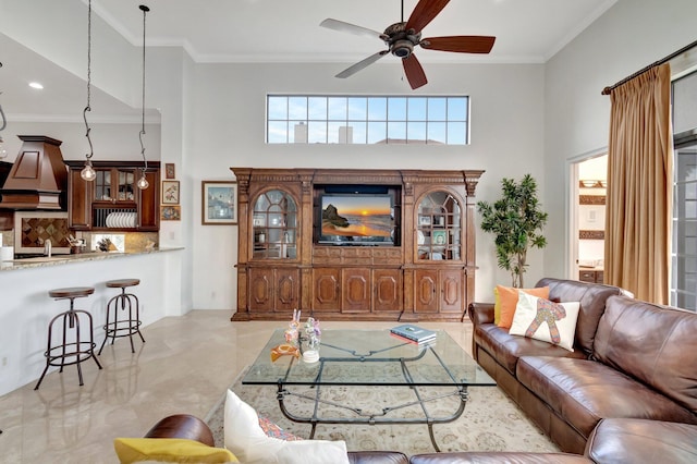 living room featuring ceiling fan, a high ceiling, and ornamental molding