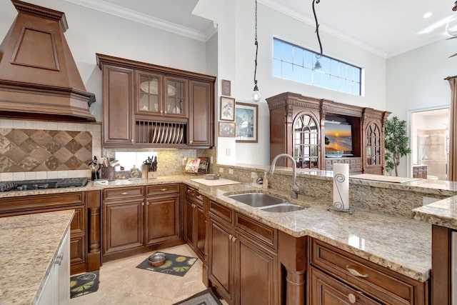 kitchen featuring sink, stainless steel gas cooktop, light stone counters, pendant lighting, and custom exhaust hood