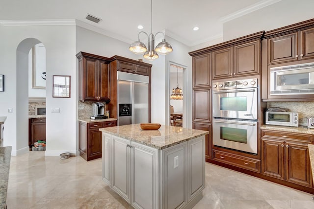 kitchen with a center island, an inviting chandelier, built in appliances, decorative backsplash, and ornamental molding