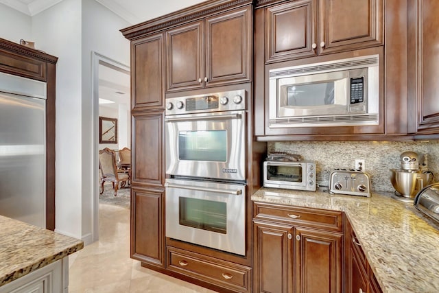 kitchen featuring built in appliances, crown molding, light stone countertops, and backsplash