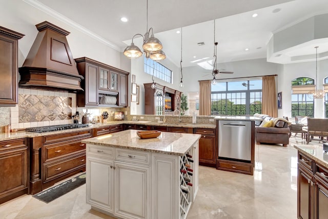 kitchen with a center island, backsplash, pendant lighting, ceiling fan with notable chandelier, and appliances with stainless steel finishes