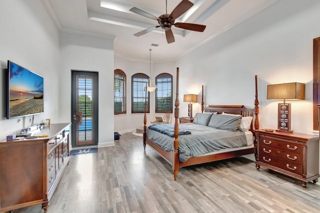 bedroom featuring light hardwood / wood-style floors, a raised ceiling, ceiling fan, and ornamental molding