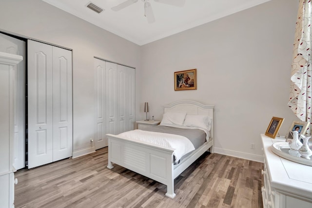 bedroom with ceiling fan, two closets, and light wood-type flooring