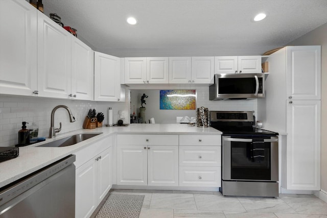 kitchen with sink, white cabinetry, a textured ceiling, stainless steel appliances, and backsplash