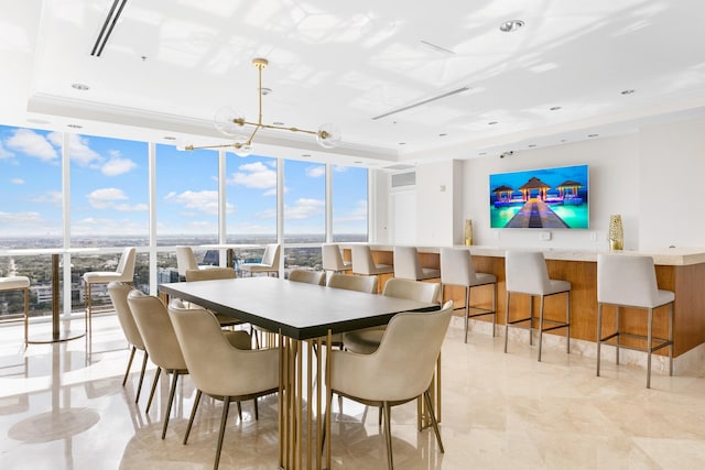 dining room featuring floor to ceiling windows, plenty of natural light, and a tray ceiling