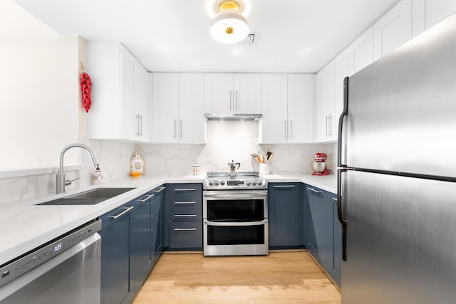 kitchen with sink, appliances with stainless steel finishes, blue cabinets, and white cabinetry