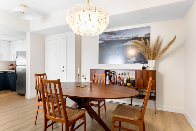 dining room with light wood-type flooring and an inviting chandelier