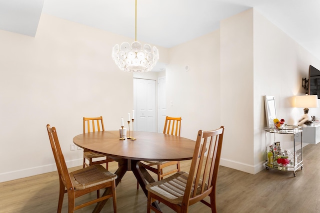 dining space with wood-type flooring and an inviting chandelier